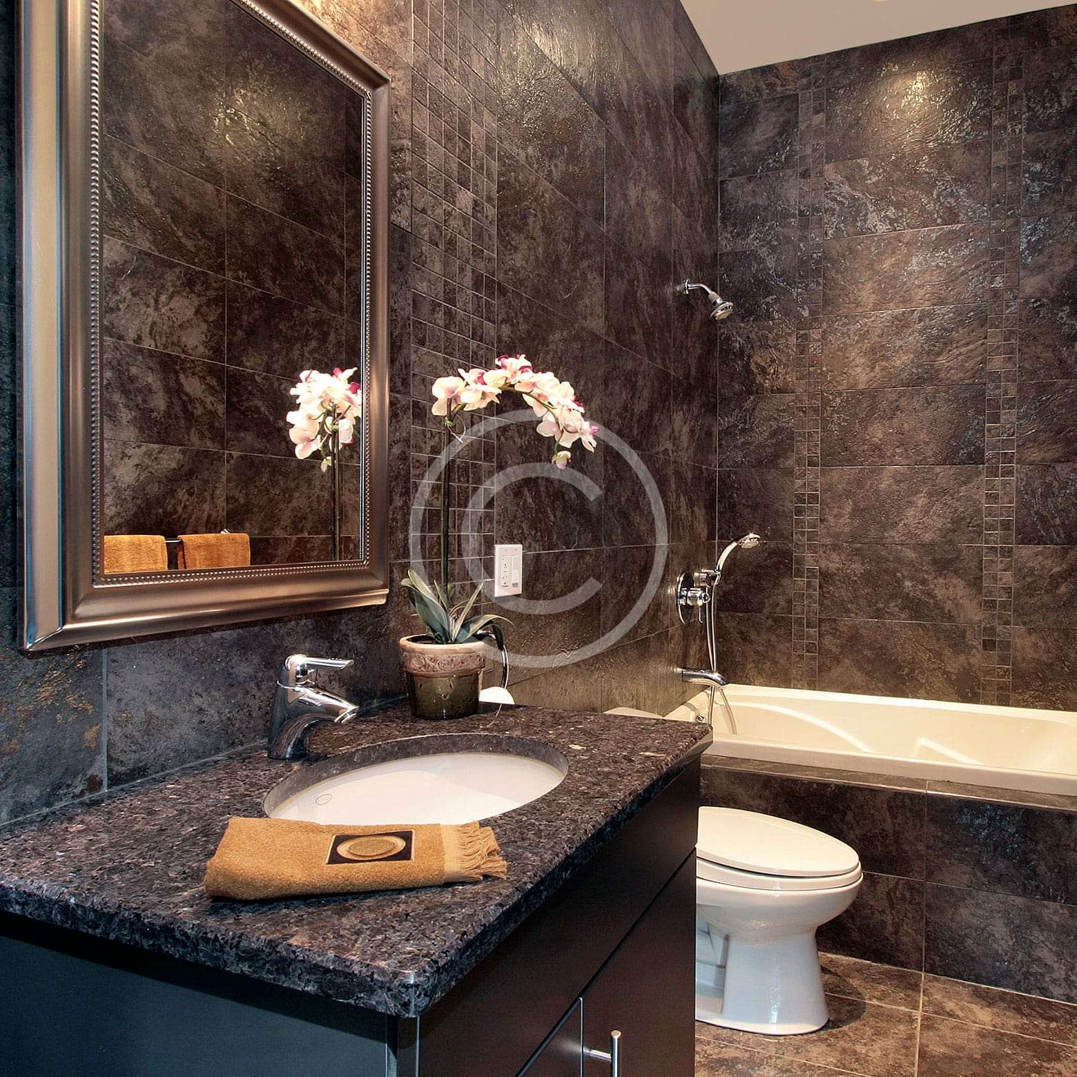 A bathroom with marble counter tops and dark walls.