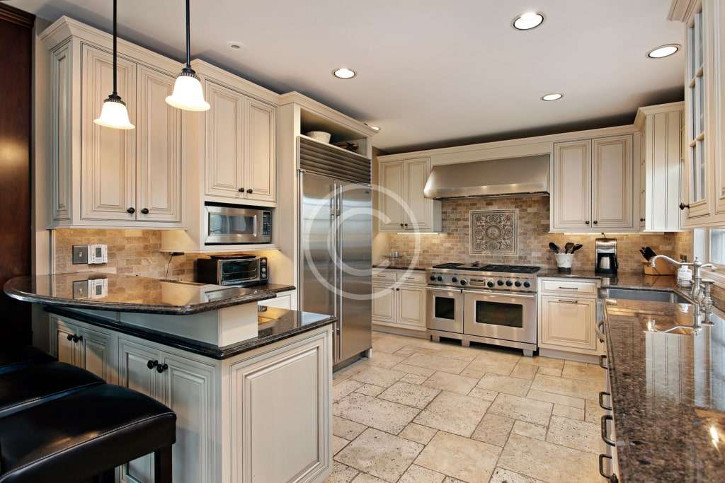 A kitchen with white cabinets and black counter tops.