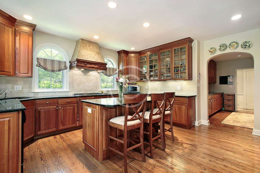 A kitchen with wooden cabinets and hardwood floors.