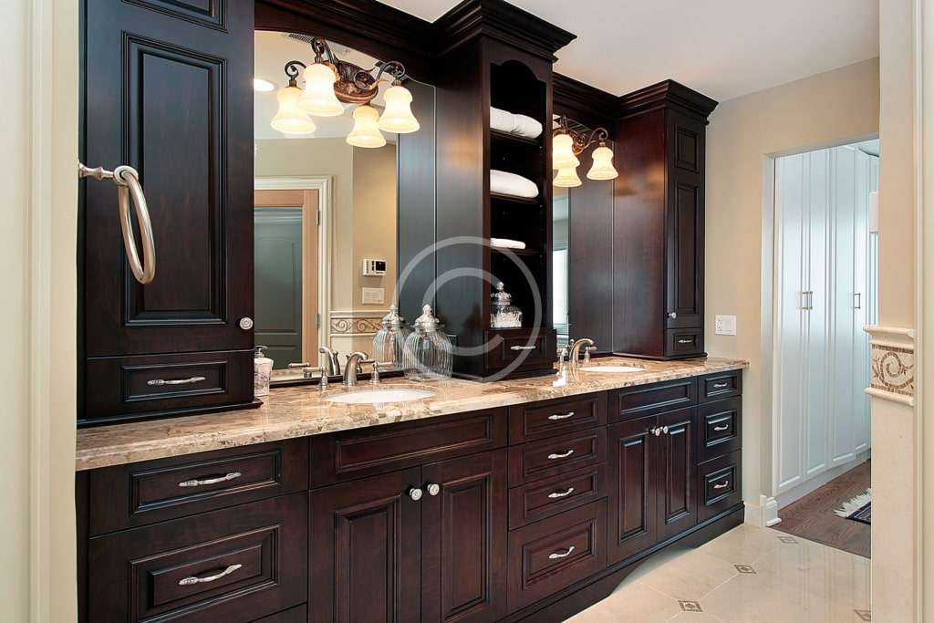 A bathroom with dark cabinets and light fixtures.