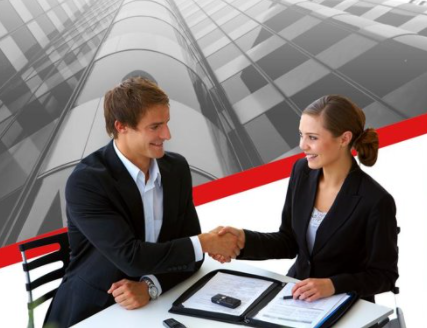 A man and woman shaking hands over papers.