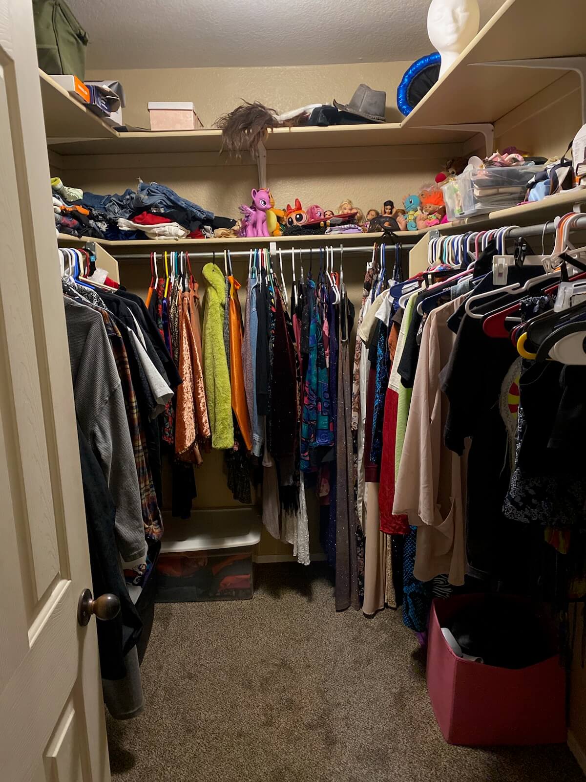 A closet with clothes and toys on shelves.